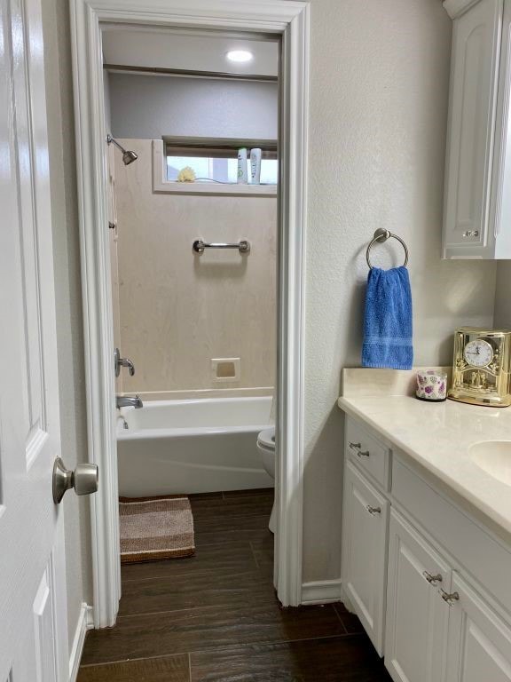 full bathroom with hardwood / wood-style flooring, vanity, tiled shower / bath, and toilet