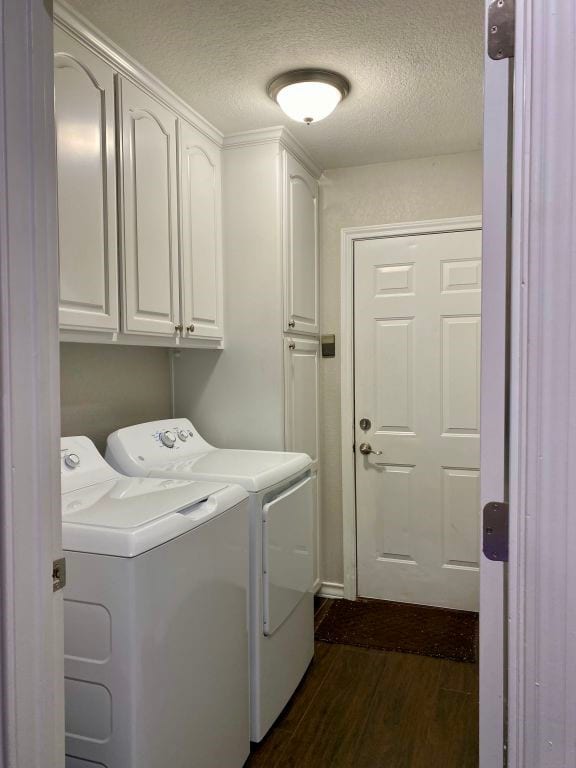 laundry room featuring cabinets, washing machine and dryer, dark hardwood / wood-style floors, and a textured ceiling