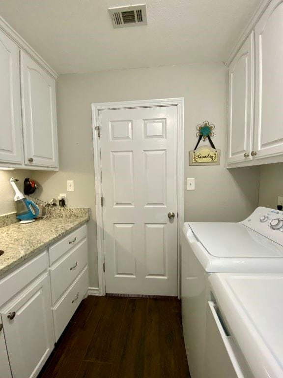 clothes washing area with dark hardwood / wood-style flooring, washer and clothes dryer, and cabinets