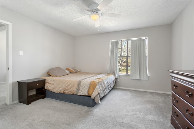 bedroom with ceiling fan, light colored carpet, and a textured ceiling