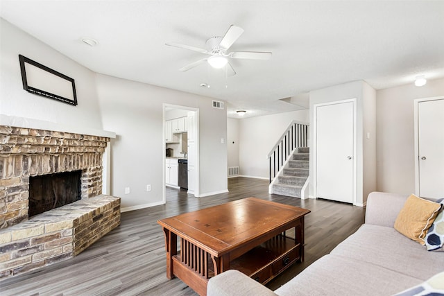 living room featuring a brick fireplace, dark hardwood / wood-style floors, and ceiling fan