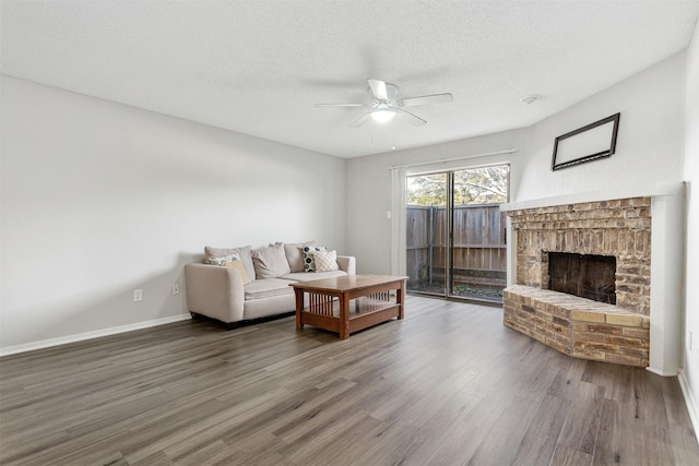 living room featuring a fireplace, wood-type flooring, a textured ceiling, and ceiling fan