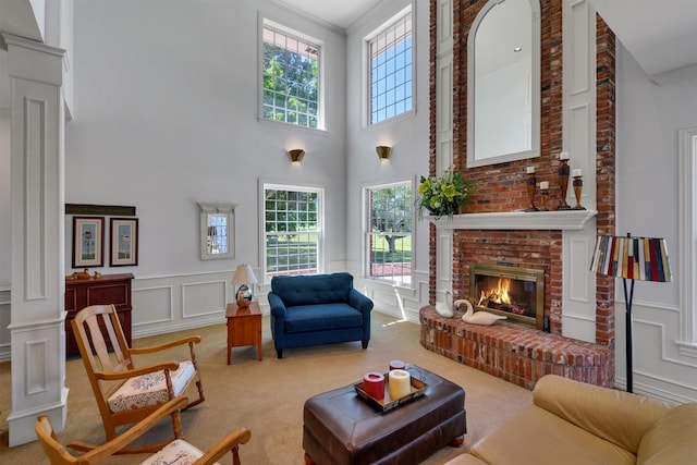 living room featuring ornate columns, light carpet, and a fireplace