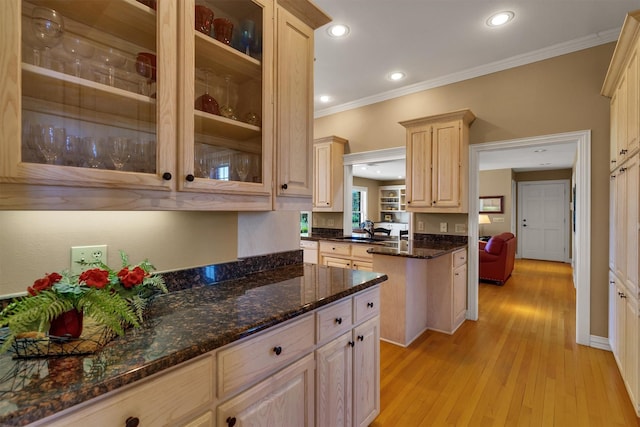 kitchen featuring sink, crown molding, light wood-type flooring, dark stone countertops, and light brown cabinets