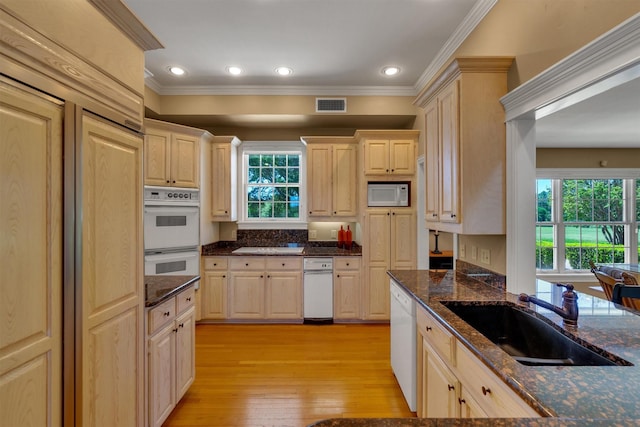 kitchen with sink, crown molding, light hardwood / wood-style flooring, dark stone countertops, and white appliances
