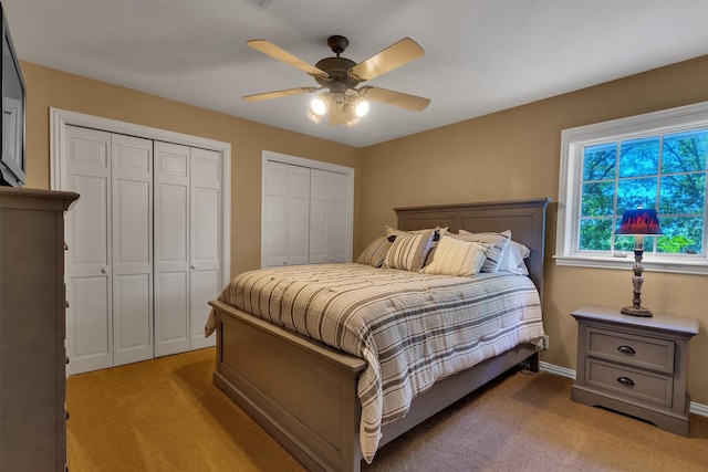 carpeted bedroom with two closets and ceiling fan
