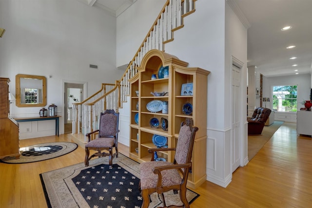 living area with a towering ceiling and light hardwood / wood-style floors