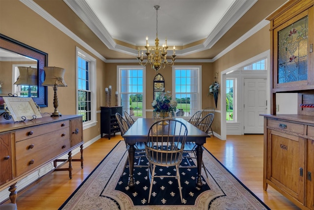 dining room featuring crown molding, a notable chandelier, light hardwood / wood-style floors, and a tray ceiling