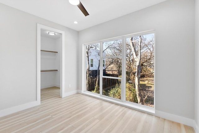 empty room featuring ceiling fan, a healthy amount of sunlight, and light wood-type flooring