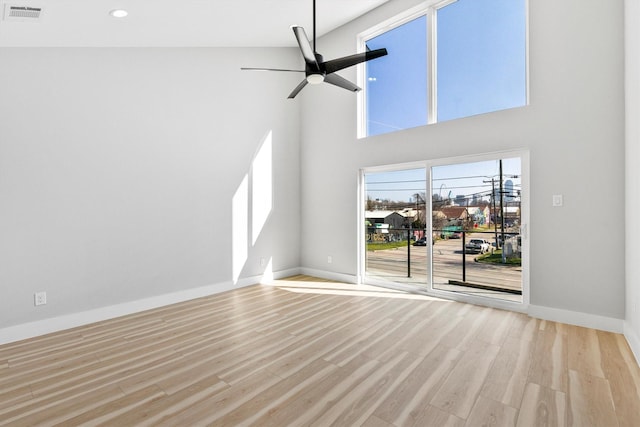 unfurnished living room with ceiling fan, light hardwood / wood-style flooring, and a towering ceiling