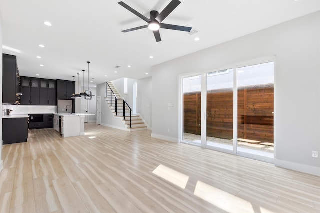 unfurnished living room with ceiling fan, light hardwood / wood-style floors, and sink