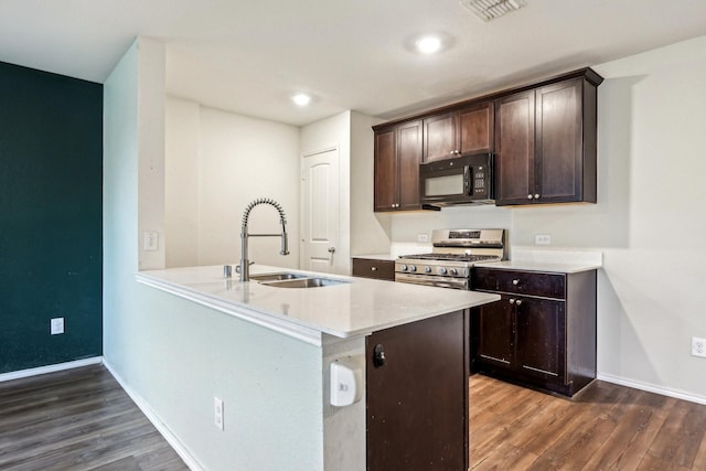 kitchen featuring sink, dark wood-type flooring, gas stove, and kitchen peninsula