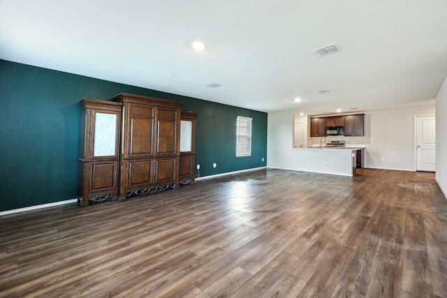 unfurnished living room featuring dark wood-type flooring and sink