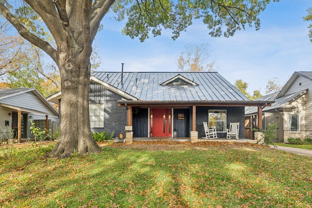 view of front of home with a front yard, a standing seam roof, covered porch, and metal roof