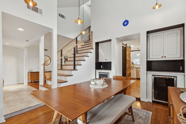 dining area featuring a barn door, wine cooler, wood finished floors, and visible vents