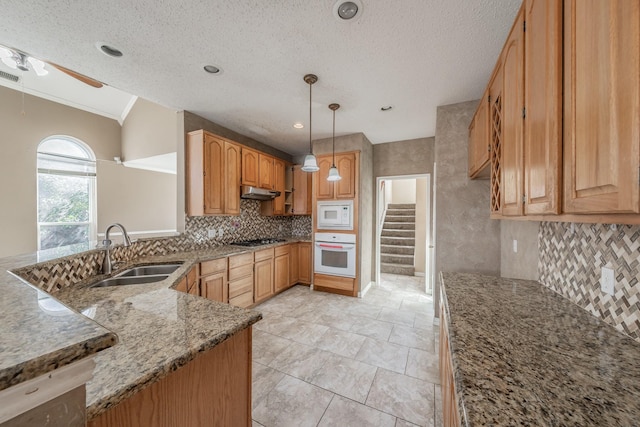 kitchen with sink, stone countertops, hanging light fixtures, white appliances, and backsplash