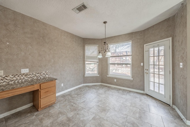 unfurnished dining area featuring a chandelier and a textured ceiling