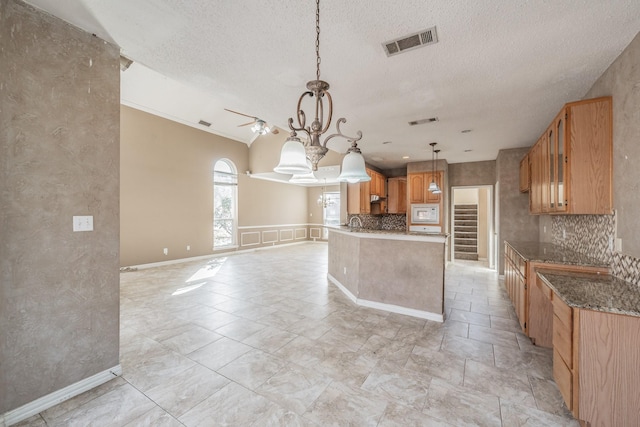 kitchen with ceiling fan, hanging light fixtures, tasteful backsplash, a textured ceiling, and stone countertops