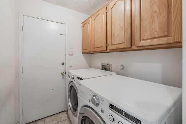 clothes washing area featuring separate washer and dryer, cabinets, and a textured ceiling