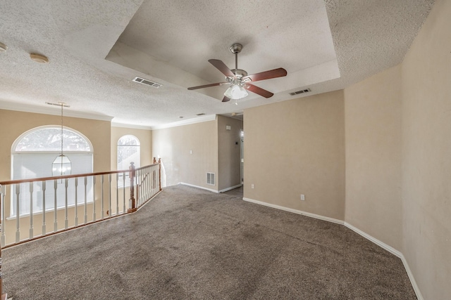 unfurnished room with a textured ceiling, ornamental molding, carpet flooring, a raised ceiling, and ceiling fan with notable chandelier