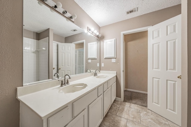 bathroom featuring vanity, a textured ceiling, and tiled shower