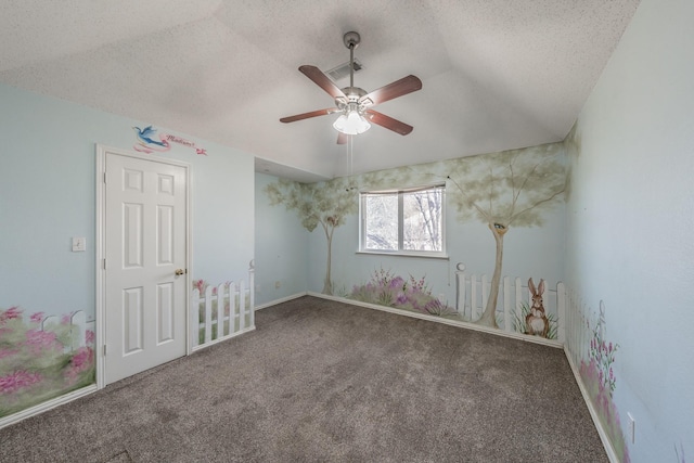 carpeted empty room with ceiling fan, vaulted ceiling, and a textured ceiling