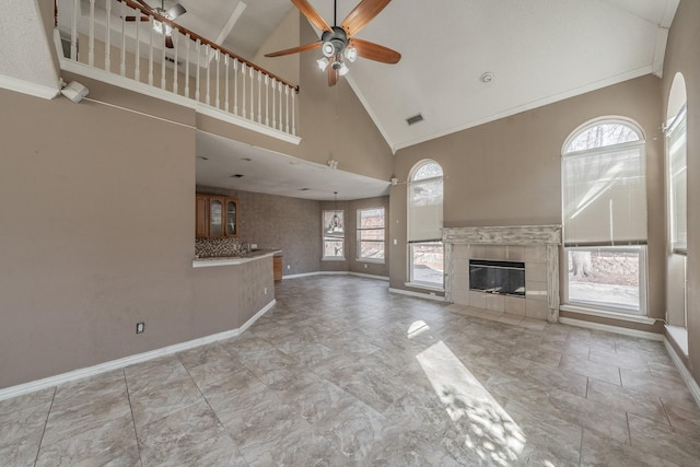 unfurnished living room featuring crown molding, ceiling fan, high vaulted ceiling, and a tile fireplace