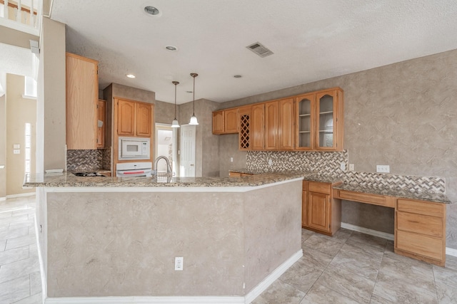 kitchen featuring tasteful backsplash, kitchen peninsula, pendant lighting, light stone countertops, and white microwave