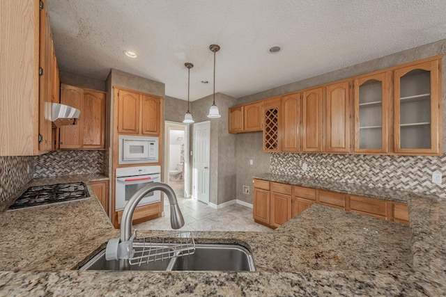 kitchen featuring sink, white appliances, backsplash, decorative light fixtures, and exhaust hood