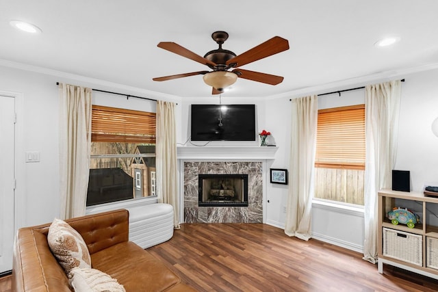 living room with hardwood / wood-style flooring, ceiling fan, ornamental molding, and a premium fireplace