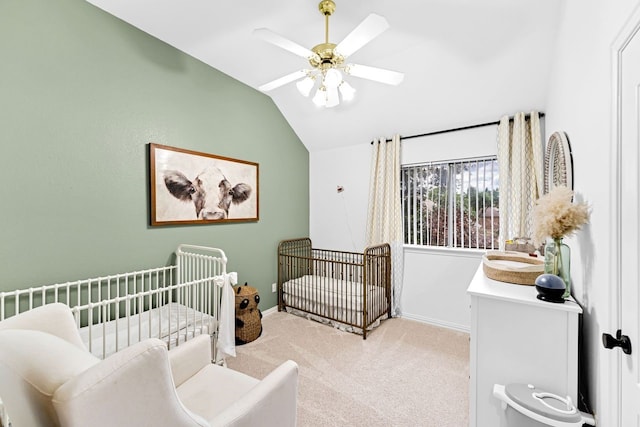 bedroom featuring a crib, vaulted ceiling, light colored carpet, and ceiling fan