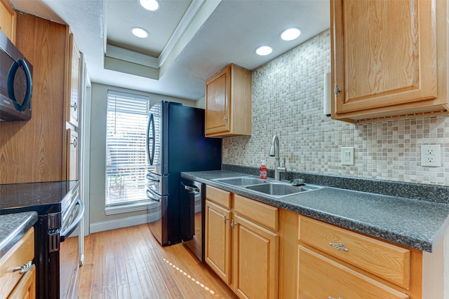 kitchen with a raised ceiling, sink, backsplash, stainless steel appliances, and light hardwood / wood-style flooring