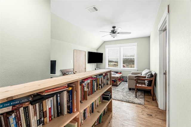 interior space featuring vaulted ceiling, a ceiling fan, wood finished floors, and visible vents
