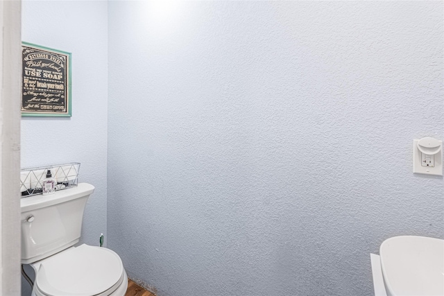 bathroom with toilet and a textured wall