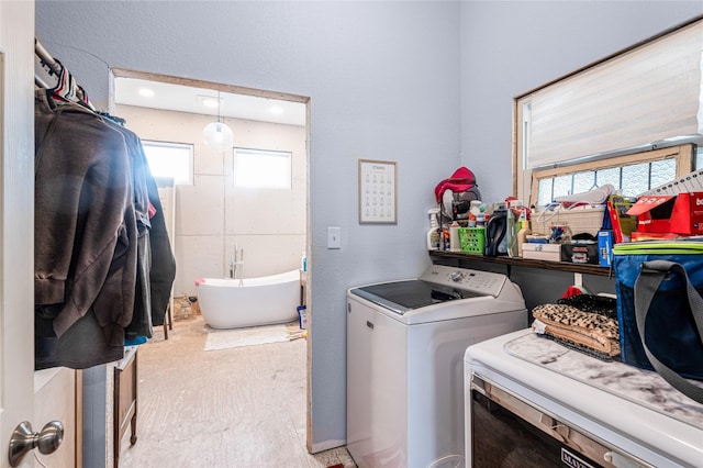 clothes washing area with a wealth of natural light, independent washer and dryer, and laundry area