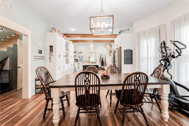 dining space with beamed ceiling, wood finished floors, and an inviting chandelier