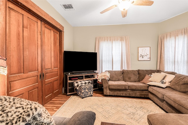 living room with wood finished floors, visible vents, and ceiling fan
