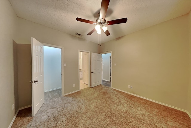 unfurnished bedroom with ceiling fan, ensuite bath, light colored carpet, and a textured ceiling