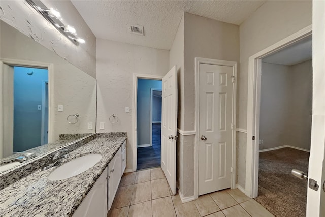 bathroom with tile patterned flooring, vanity, and a textured ceiling