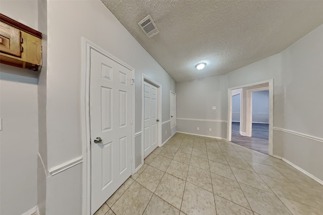 empty room with light tile patterned floors and a textured ceiling