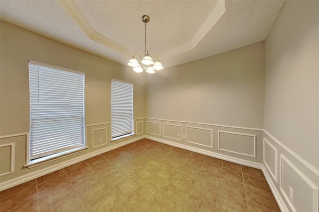 spare room with a tray ceiling, a chandelier, a textured ceiling, and light tile patterned floors