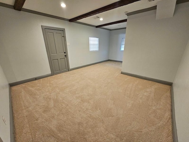 spare room featuring light colored carpet and beamed ceiling