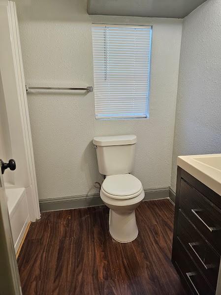 full bathroom featuring wood-type flooring, toilet, shower / bathing tub combination, and vanity