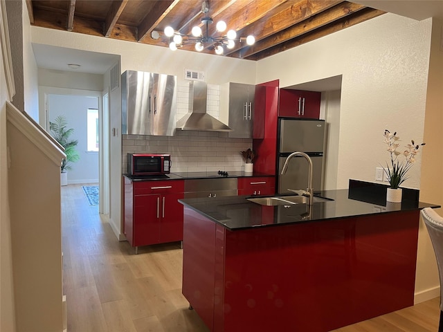 kitchen with black electric stovetop, freestanding refrigerator, a sink, dark countertops, and wall chimney range hood