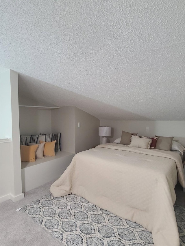 bedroom with vaulted ceiling, carpet floors, and a textured ceiling