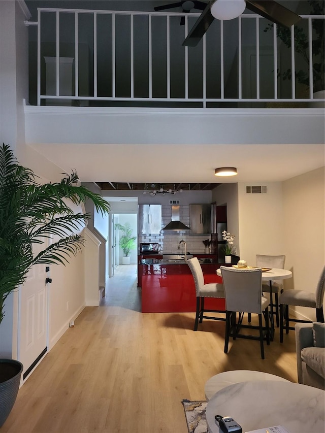 interior space with sink, light hardwood / wood-style flooring, ceiling fan, and a high ceiling