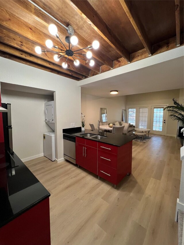 kitchen featuring stainless steel dishwasher, stacked washer and clothes dryer, sink, and light wood-type flooring