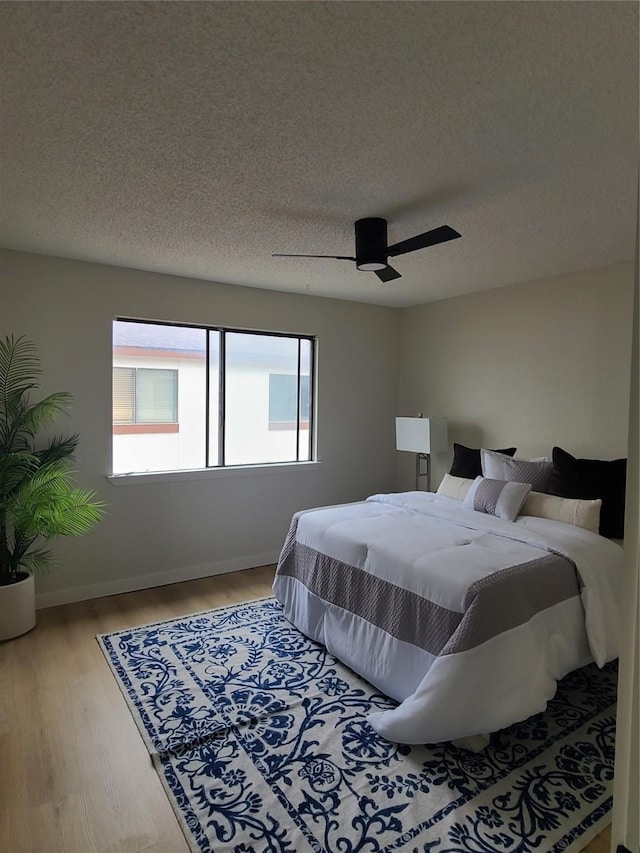 bedroom with hardwood / wood-style flooring, a textured ceiling, and ceiling fan