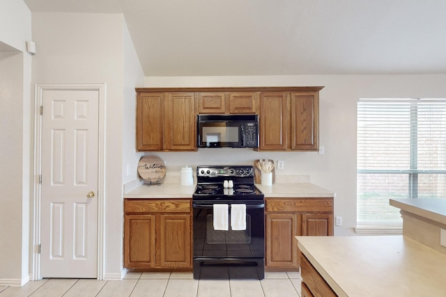 kitchen with a healthy amount of sunlight, light tile patterned floors, and black appliances