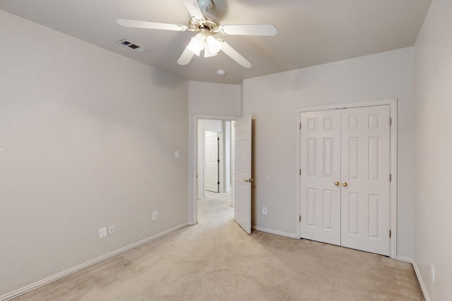 unfurnished bedroom featuring light carpet, a closet, and ceiling fan